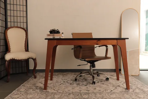 Mesa de madeira com cadeira, biombo preto, cadeira clássica e espelho oval no Studio Criativo
