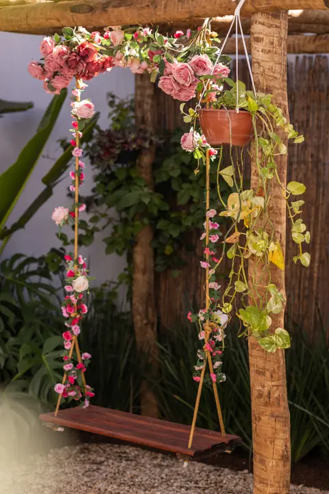 Balanço de madeira com flores e plantas pendentes no jardim da Mansão