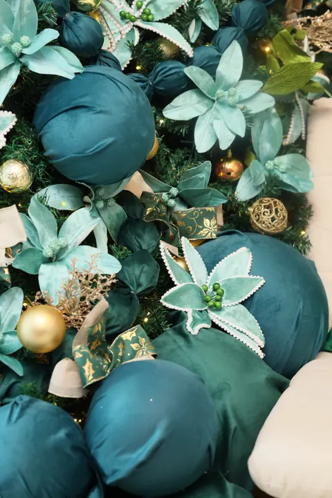 Detalhe de flores azul-turquesa, bolas de veludo e enfeites dourados da decoração de Natal