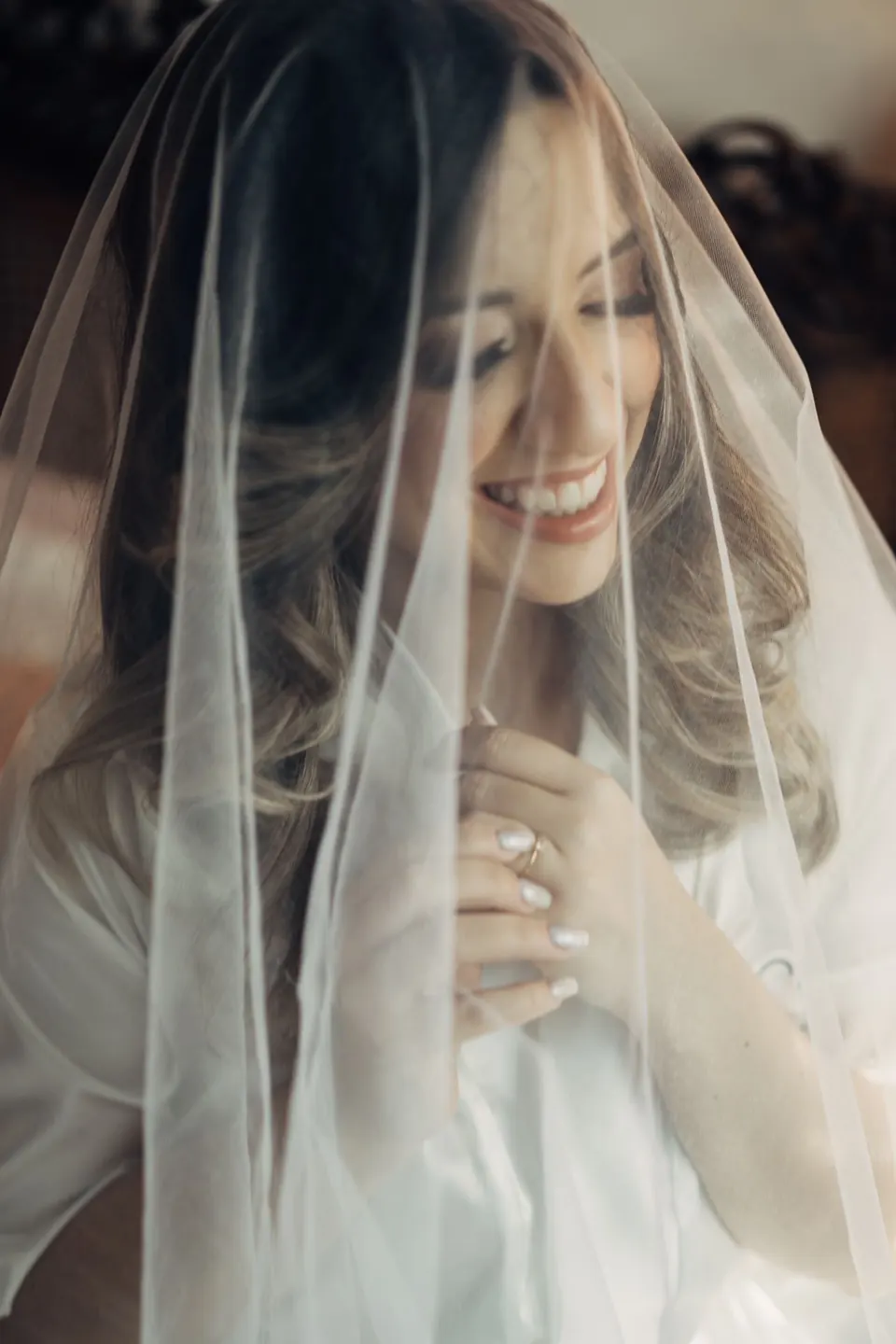 Noiva sorrindo por baixo do véu no Dia da Noiva
