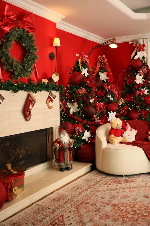 Lareira com meias, árvores iluminadas e poltrona branca no Natal do Loft Oásis