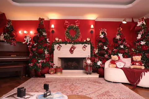 Lareira decorada, poltrona com manta vermelha e árvores de Natal no Loft Oásis